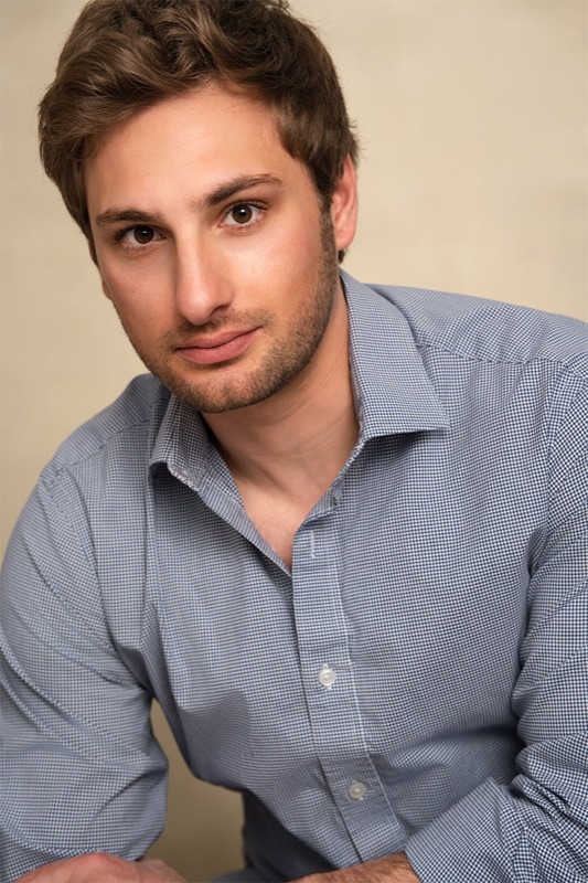 Actor headshot, direct to camera, warm neutral backdrop