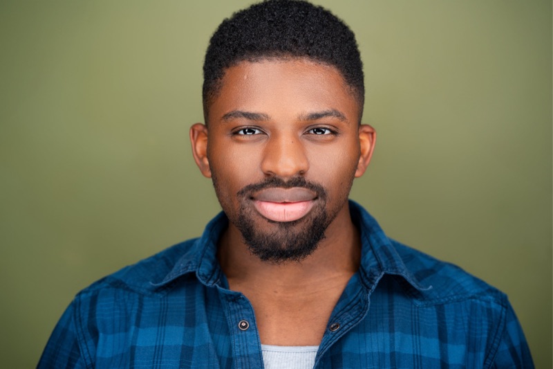 Actor headshot against an olive backdrop